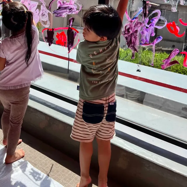 屋上のガラスに絵の具でお絵かきする園児（後ろ姿）